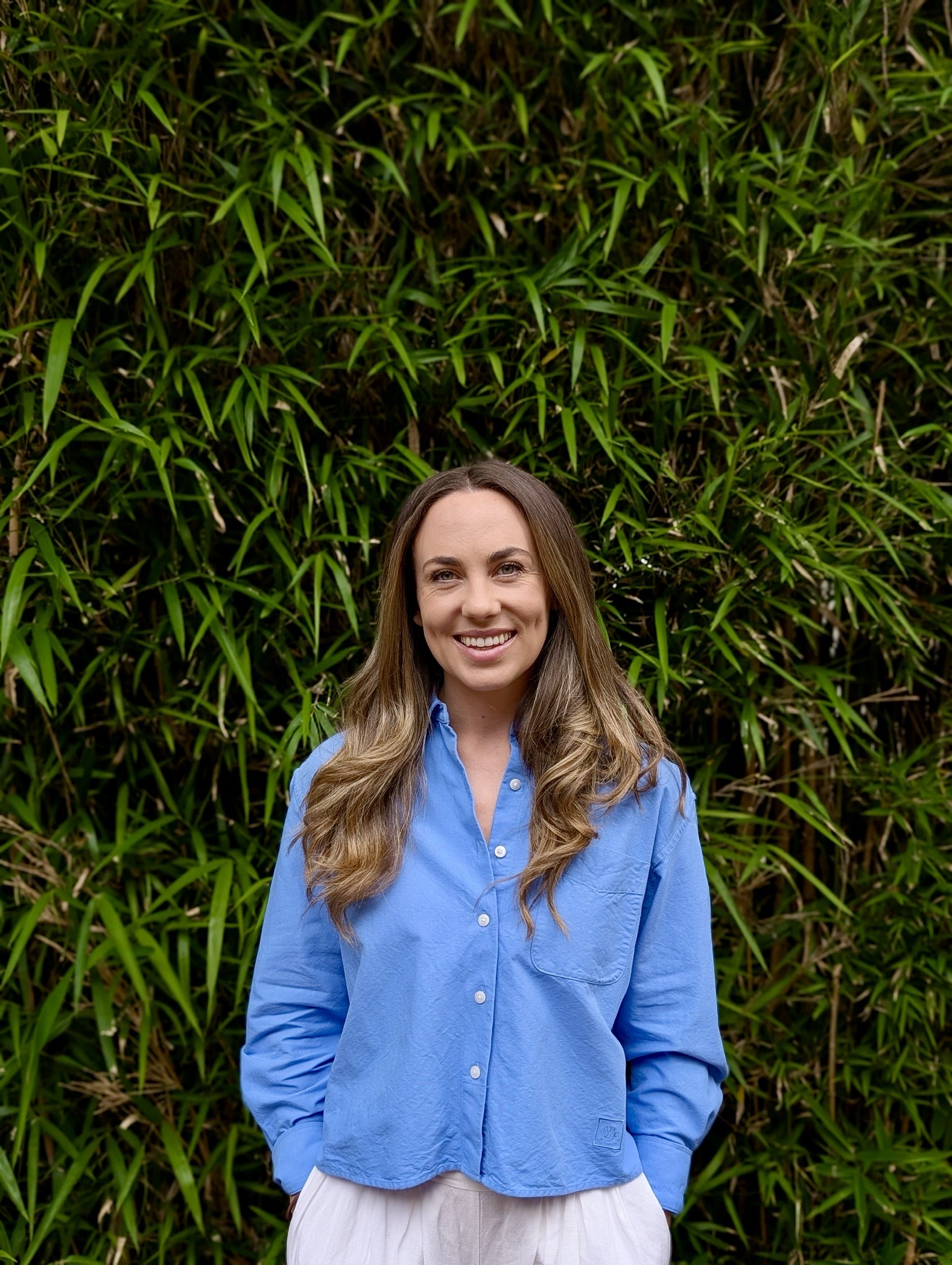 Imagene Callinan, Practitioners member at Akashahealth, smiles in front of a lush green